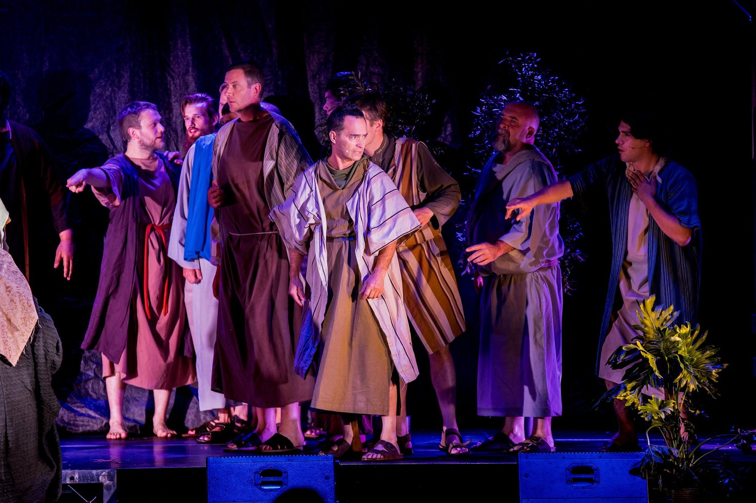 Disciples on stage in the garden, one man held by the shoulder