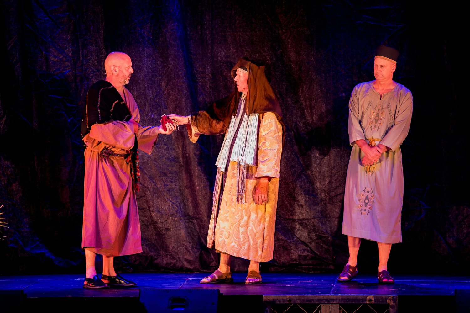 Three performers in costume during a night scene